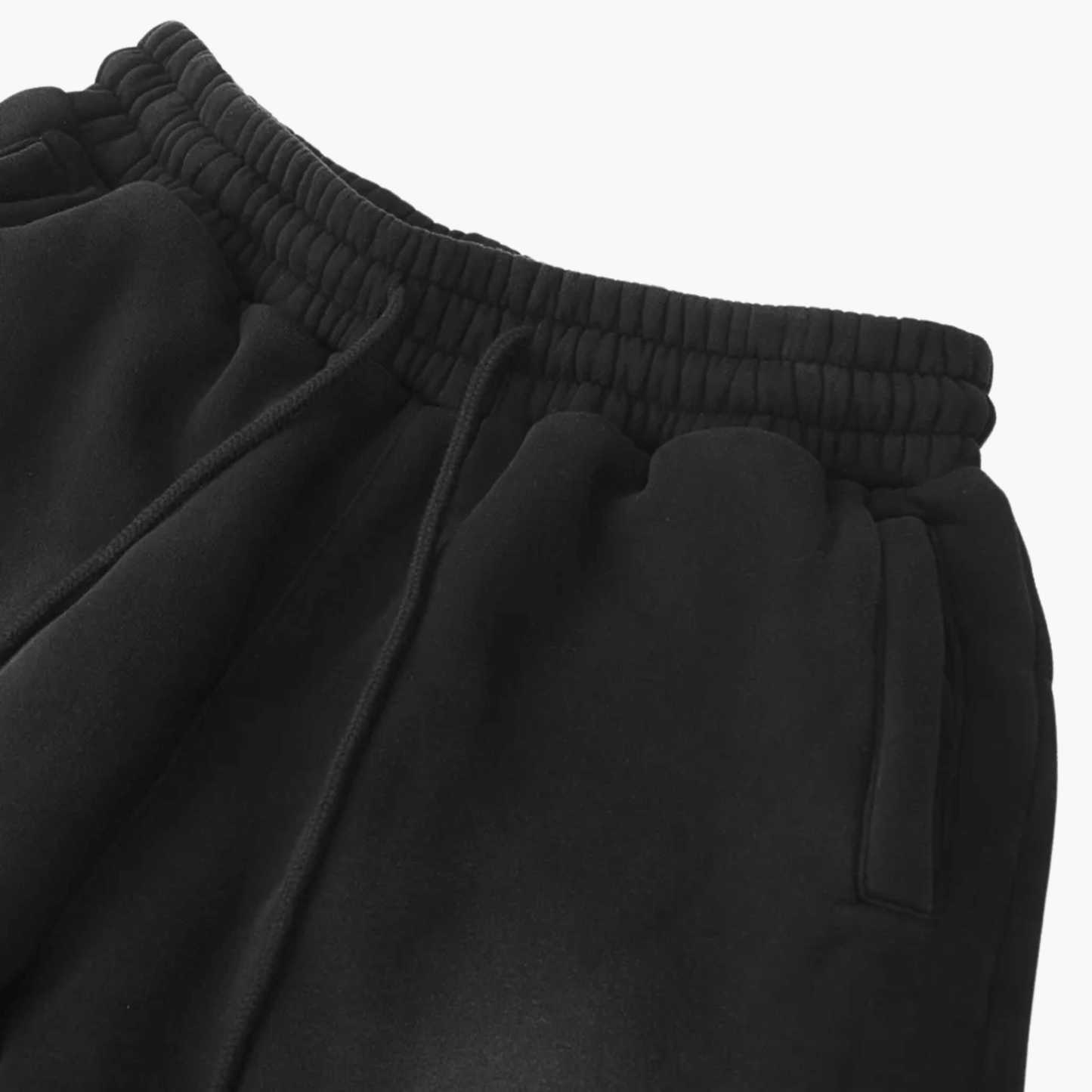 Close-up of black sweatpants showcasing the elastic waistband and pockets, perfect for casual style.