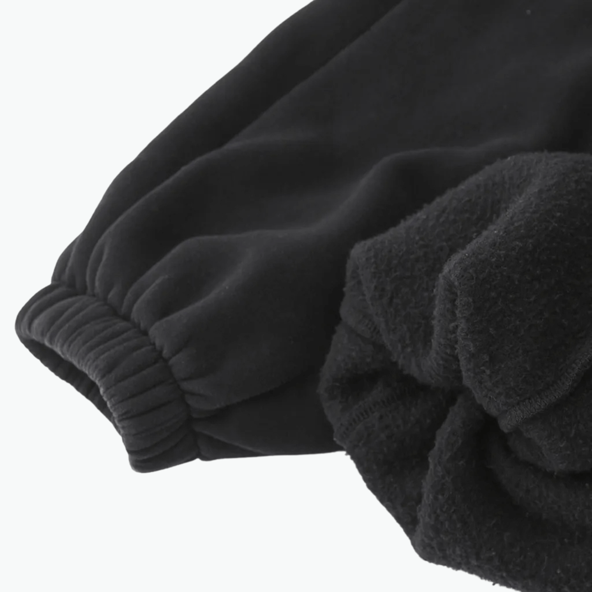 Close-up of black Kalispera sweatpants detailing, showcasing soft fabric and textured finish.