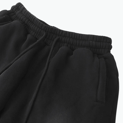 Close-up of black sweatpants showcasing the elastic waistband and pockets, perfect for casual style.